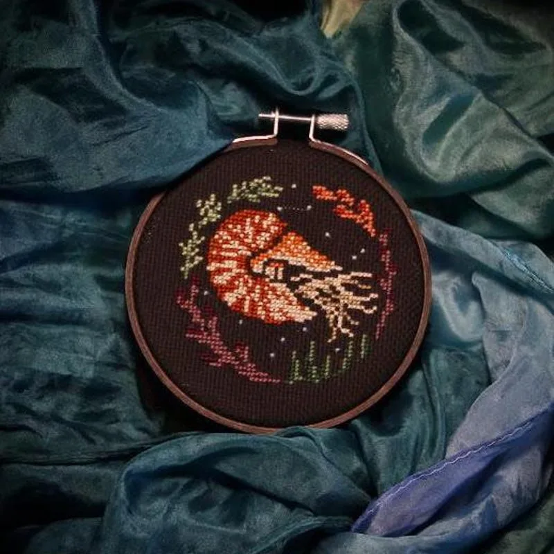 Finished nautilus hoop resting on softly folded blue and green fabric